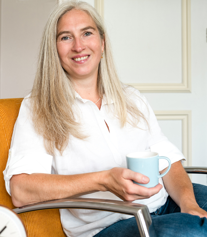Mindset transformation coach Dagmar Hopf smiling and holding a mug, ready for a chat